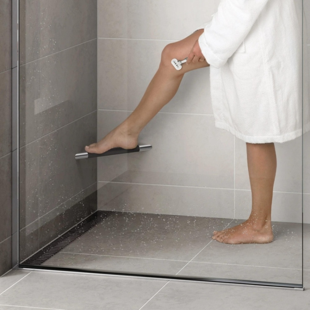 Product Lifestyle image of someone using the HIB Corner Grab Bar with Grip as a footrest